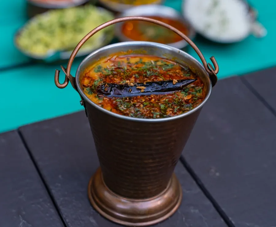 Curry served in a copper bucket on a teal table