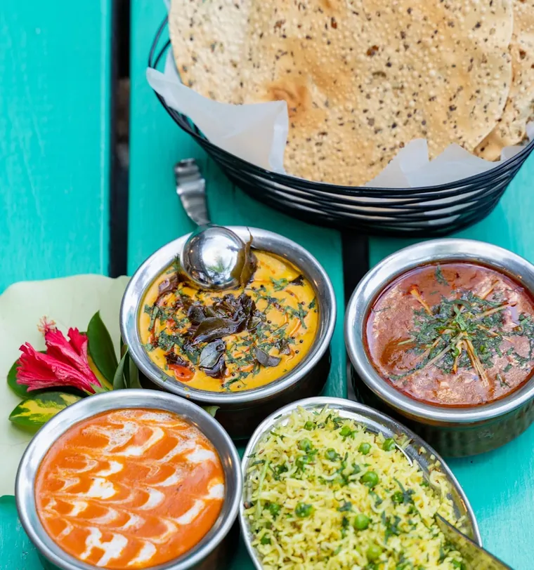 Indian curries, rice and papad served on a teal table