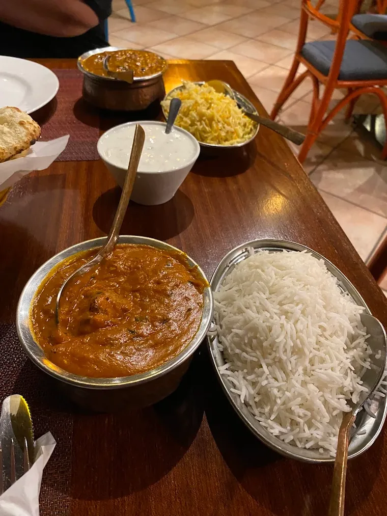 Curry, basmati rice, raita and naan on a restaurant table